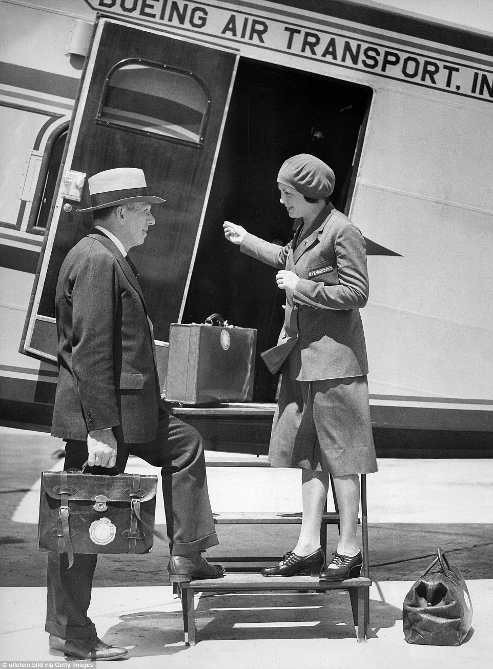 Church stands on airplane step welcoming a crew member holding a briefcase