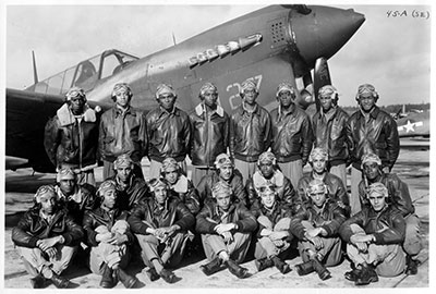 black and white photo of the Tuskegee Airmen posing in front of plane
